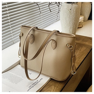 Close-up of beige tote bag with litchi texture and elegant gold hardware rings