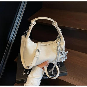 Close-up of cream glossy pleated leather bag with silver heart star charms and hardware