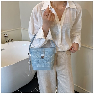 Détail du sac seau bleu clair à texture tissée avec fermoir en métal argenté et anse