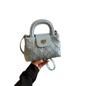 Light blue denim handbag with quilted heart buckle for hand or crossbody wear