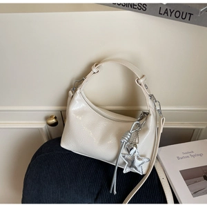 Detail of creamy white hobo bag with glossy finish and silver star heart charm