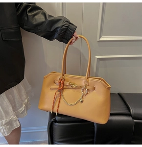 Dettaglio della borsa tote beige con catena in metallo e corda intrecciata arancione