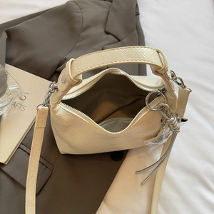 Macro view of cream pleated PU leather handbag with silver star charm and metallic zipper
