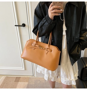 Dettaglio di una borsa a spalla in pelle marrone con fibbie vintage e occhielli in metallo
