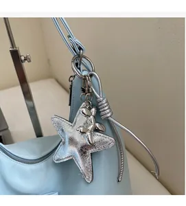 Detail of light blue bag featuring a large silver star charm and metal balloon dog pendant