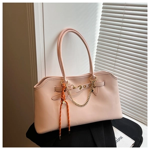 Detail of pink PU leather tote bag with gold chain and orange knotted handle charm