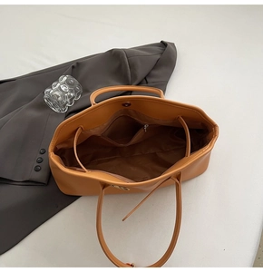 Vista interna della borsa tote in pelle marrone che mostra l'ampio scomparto e la tasca con zip