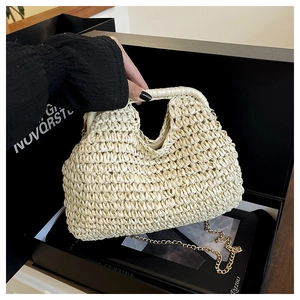 Détail de sac en paille tressée crème avec texture fine et bandoulière en chaîne dorée
