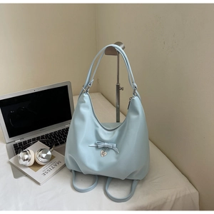 Detail of light blue nylon handbag featuring a ribbon bow and heart metal pendant