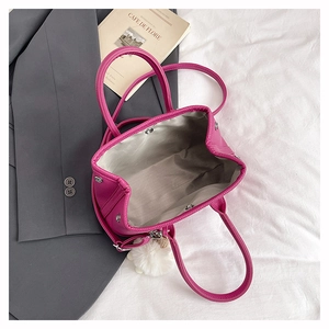 Detailansicht der pinkfarbenen Handtasche mit grauem Innenfutter und weißem Plüschanhänger