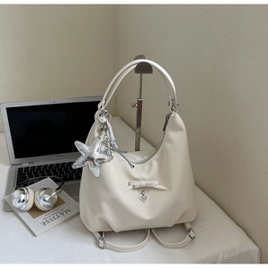 Detail of cream multi-functional backpack with bow charm and silver star pendant