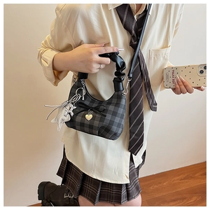 Dettaglio di mini borsa a quadri grigi con fiocco di seta e ciondolo a cuore dorato elegante