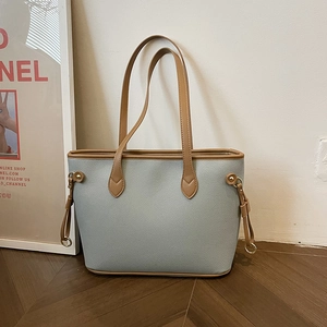Blue lychee leather tote bag with brown straps and drawstring detail in a modern room