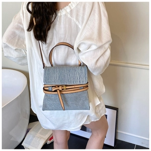 Detailed close-up of denim tote bag featuring leather straps and metal buckle accents