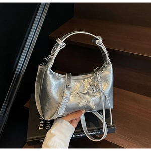 Silver metallic dumpling shoulder bag with star and heart charms on a wooden background
