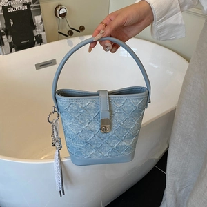 Sac seau bleu clair à texture tressée et pompon en chaîne argentée au style minimaliste