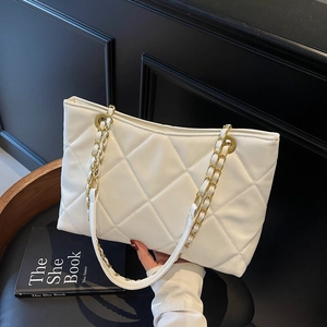 Borsa tote trapuntata bianca con catena dorata su sedia nera, borsa a spalla alla moda