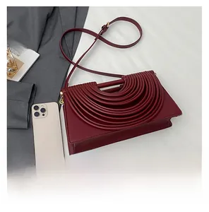 Sac bandoulière bordeaux plissé avec un smartphone blanc pour comparer la taille sur tissu