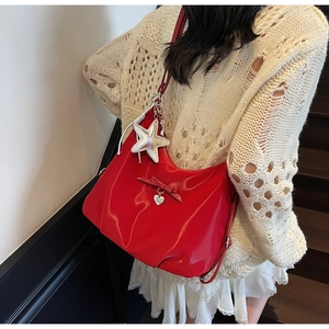 Detail of red patent leather shoulder bag with bow, heart pendant, and large silver star