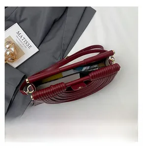 Détail macro du sac à bandoulière tissé bordeaux avec grande capacité et fermoir magnétique doré
