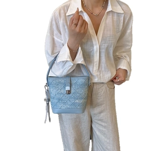 Sac seau bleu clair avec texture tissée, pompon et fermoir argenté pour femmes