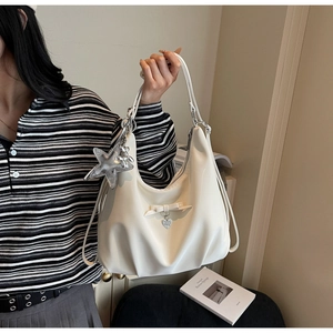 Detail of white puffer shoulder bag with metallic star charm and ribbon bow decoration