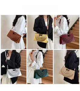 Sacs bandoulière carrés plissés modernes en six couleurs sur modèle dans un escalier