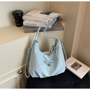 Detail of light blue hobo bag with ribbon bow, heart pendant and metallic chain strap