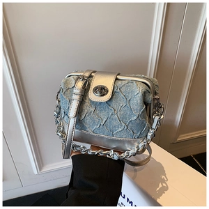 Detailed close-up of quilted denim texture and silver metal turn lock on a stylish handbag