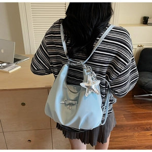 Detail of light blue crescent backpack featuring bow details and silver star pendant