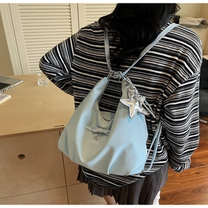Detail of light blue hobo bag with ribbon bow, heart pendant, and silver star charm
