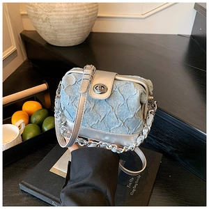 Detail of blue denim mini bag with silver leather trim and metal rotary lock clasp