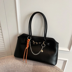 Borsa hobo in pelle nera opaca con catena dorata e ciondolo arancione sulla sedia