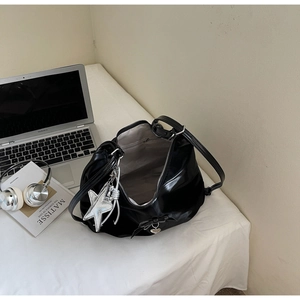 Close-up of black patent leather bag with bow detail and silver star charm in city office set