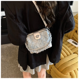 Detail view of silver textured quilted box bag with metal chain strap on shoulder
