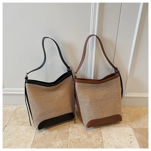 Detail of woven straw bucket bag with contrasting leather trim and texture