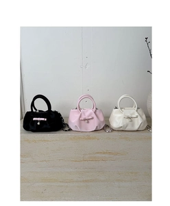 Detail of elegant pleated mini handbags with bow accents and pearl charms in three colors