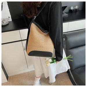 Detail of woven straw shoulder bag with black leather trim and fine texture finish