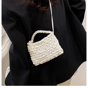 Détail d'un mini sac bandoulière blanc tissé main avec texture de corde sur costume noir