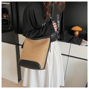 Detail showing the straw woven bucket bag with black leather base and texture