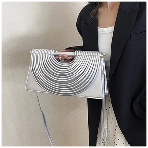 Petit sac argenté avec texture striée et poignée en métal porté par un mannequin