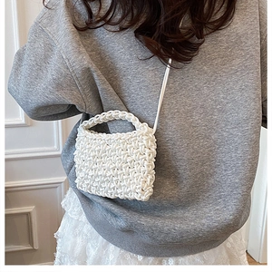 Gros plan d'un sac bandoulière blanc tressé à la main avec poignée et texture riche