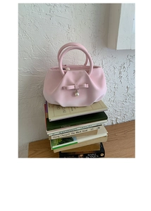 Detail of light pink cloud pleated handbag with bow, pearl pendant and metal ring handles