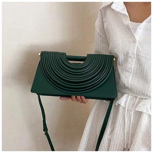 Détail du sac à bandoulière en cuir vert foncé avec design plissé semi-circulaire unique