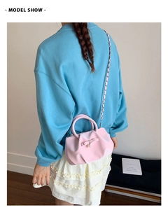 Pink pleated bag with bow and pearl detail shown from a model's back view style