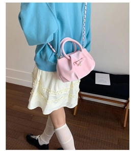 Detail of pink bow handbag showing pleated cloud texture and elegant pearl pendant