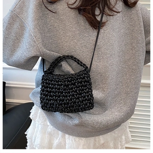 Détail d'un sac noir tissé à la main avec texture épaisse porté par un mannequin