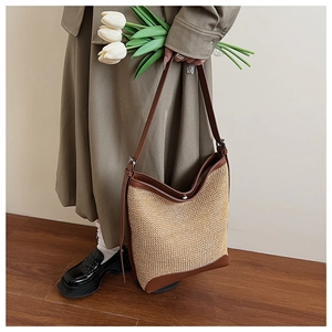 Detail of hand-woven straw tote with brown leather straps and metal magnetic closure