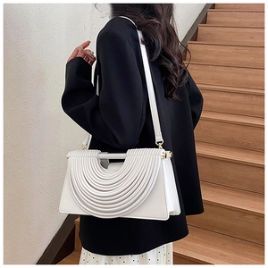 Vue détaillée du sac bandoulière blanc avec texture plissée demi-cercle sur un escalier