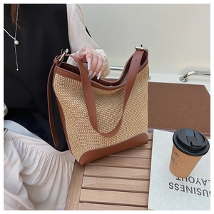 Close-up of woven tote bag with dark brown leather trim and handle details